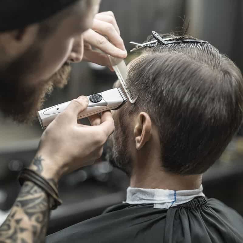 Barbero recortando cabello masculino con máquina en Miguel Hidalgo.