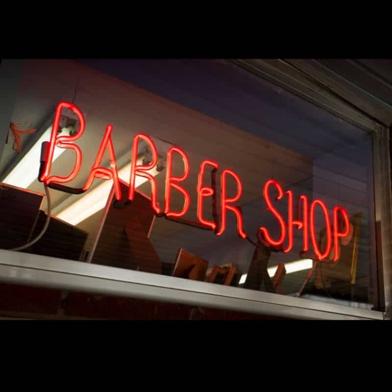 Letrero luminoso de BARBER SHOP en neón rojo.