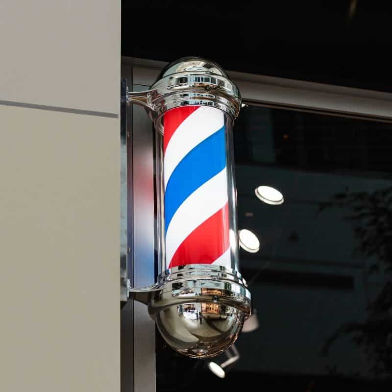 Póster tradicional de barbería con franjas rojas, blancas y azules.