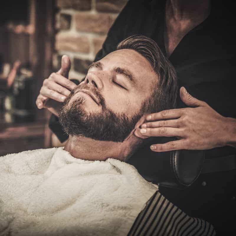 Barbero afeitando barba con navaja clásica en barbería de Miguel Hidalgo.